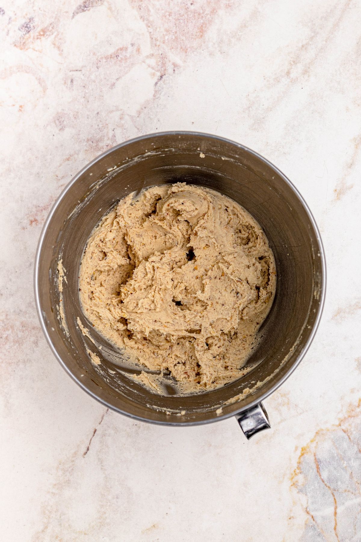 Snowball cookie dough, mixed together in a silver bowl.