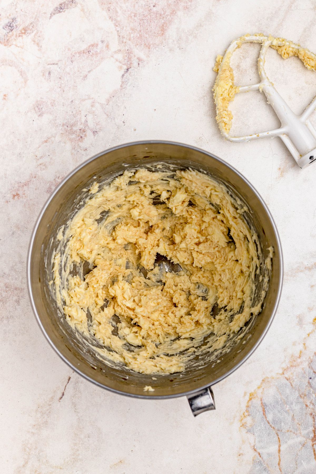 Butter and sugar, creamed together in a silver mixing bowl.