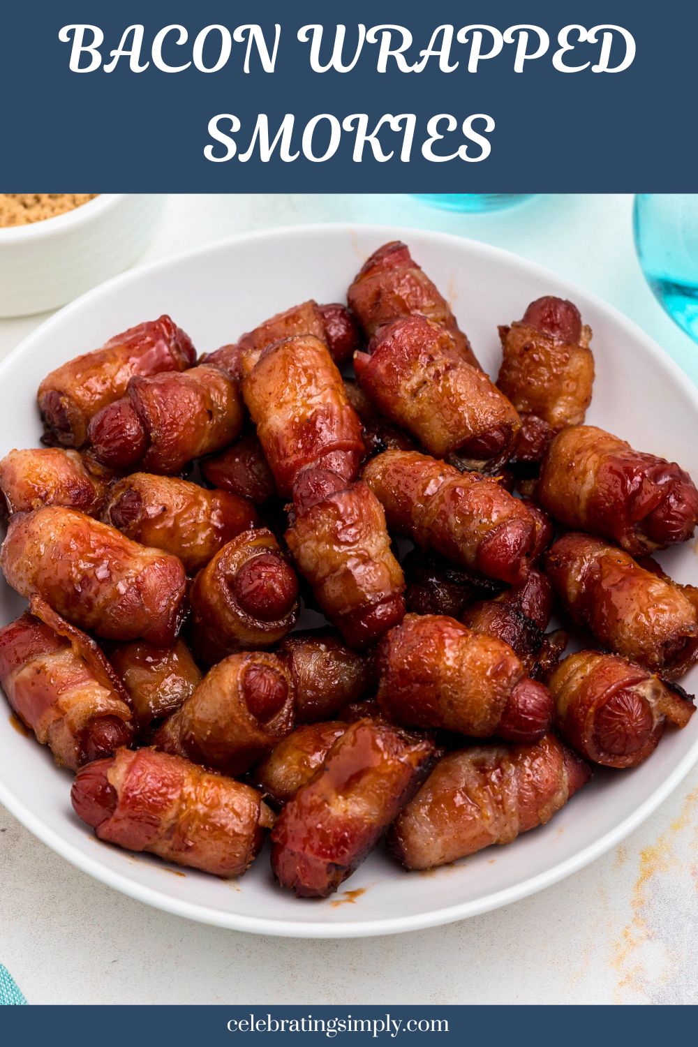 Golden bbq coated bacon wrapped smokies on a white plate with blue glasses of water on the table.