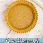 Golden uncooked pie crust in a pie plate, with fluted fork holes.