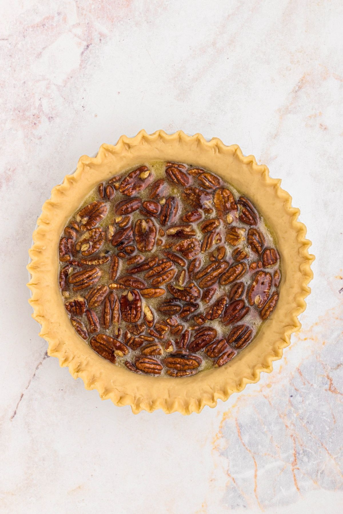Pecans, eggs, and corn syrup, mixed together with sugar and other ingredients,  then poured into an unbaked pie crust. 