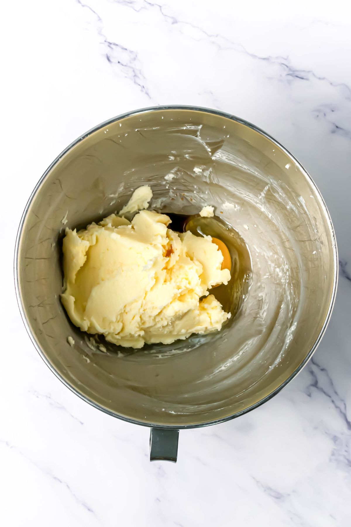 Soft dough of butter and sugars, mixed together in a silver bowl.