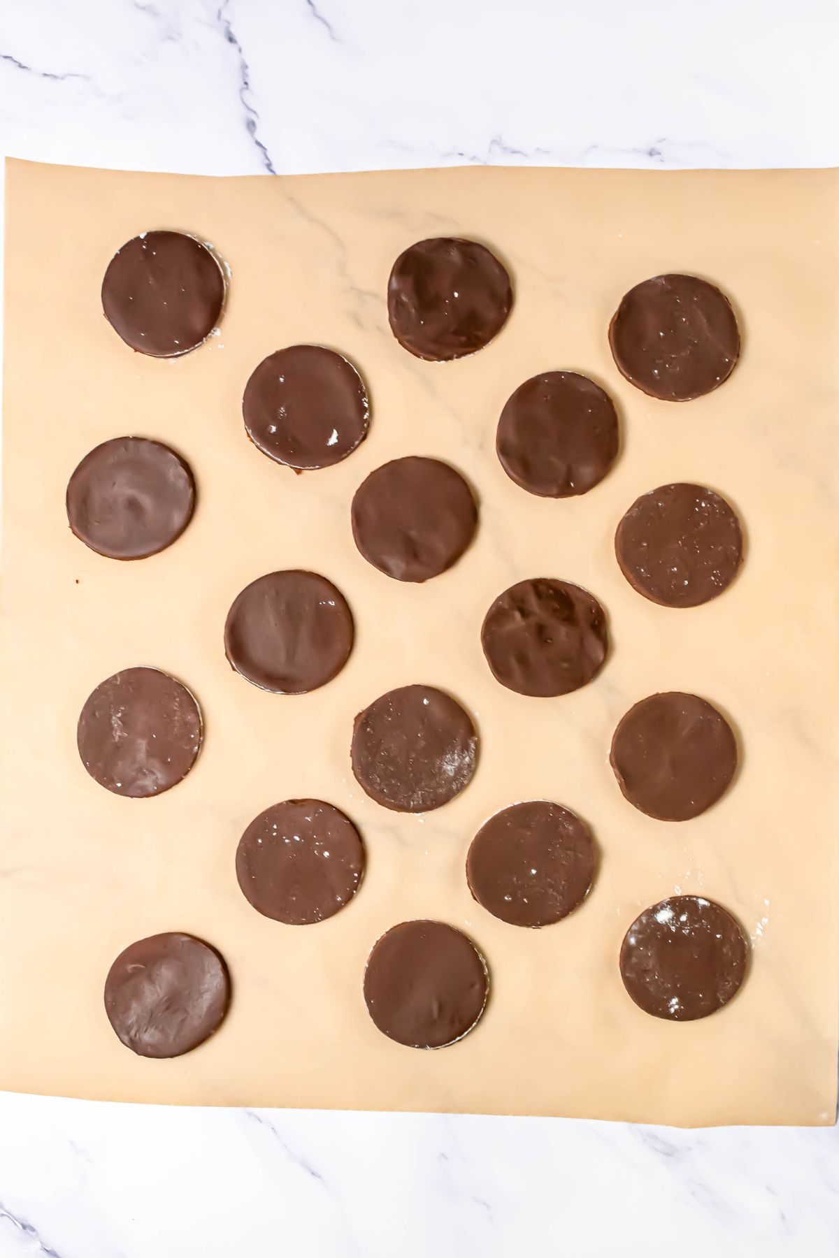 Chocolate cookies dipped in melting chocolate, then placed on a parchment paper to dry.