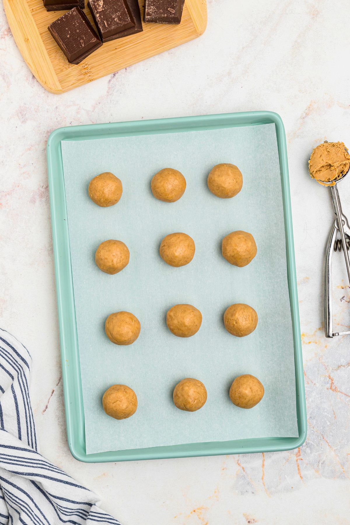 Scoops of peanut butter filling on a parchment paper lined sheet. 