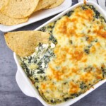 Creamy dip in a square dish with a tortilla chip dipping some out.