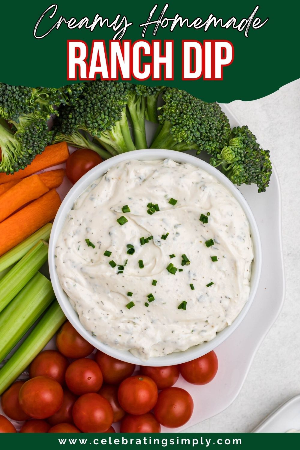 Small white bowl filled with dip, surrounded by fresh vegetables on a white plate, on table.