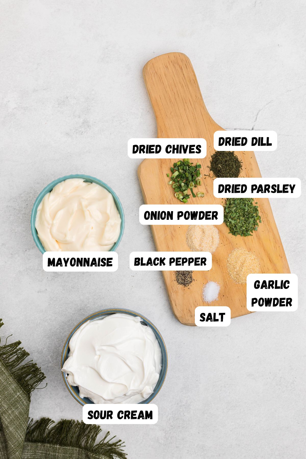 Ingredients of mayo, sour cream, dried dill, parsley, garlic powder, and other seasonings needed to make ranch dip, measured out and labeled.