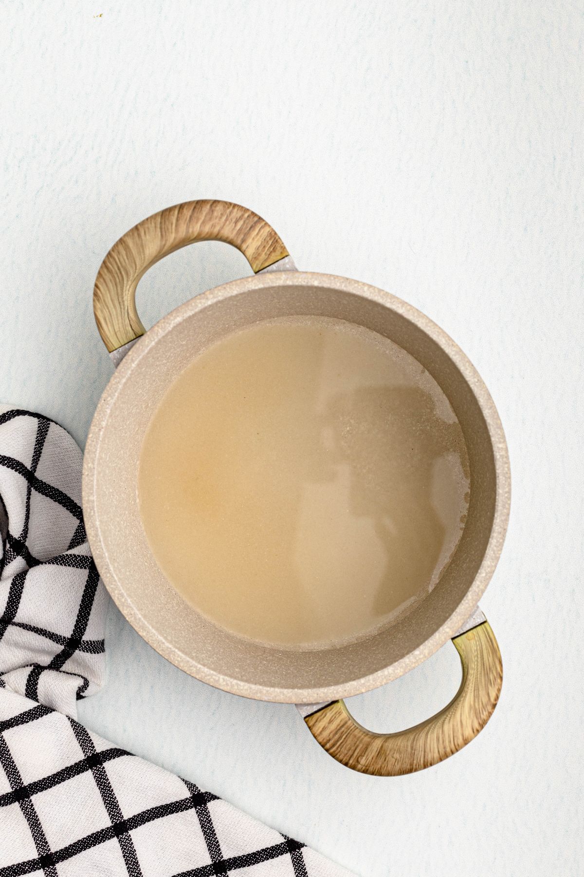 Sugar and water in a saucepan on a table, with a black and white linen, before being heated and dissolved. 