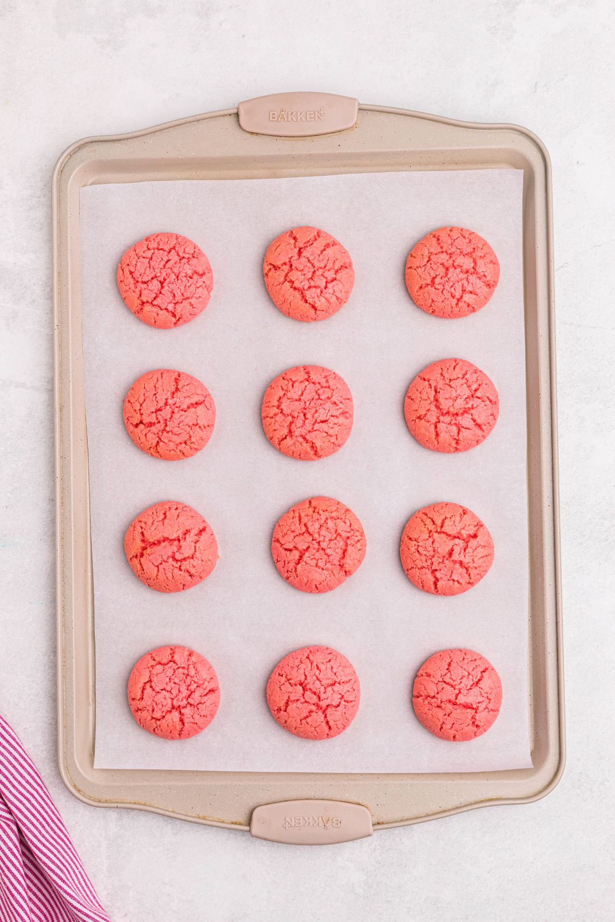 Pink strawberry cake mix cookies baked on a baking sheet, lined with parchment paper .