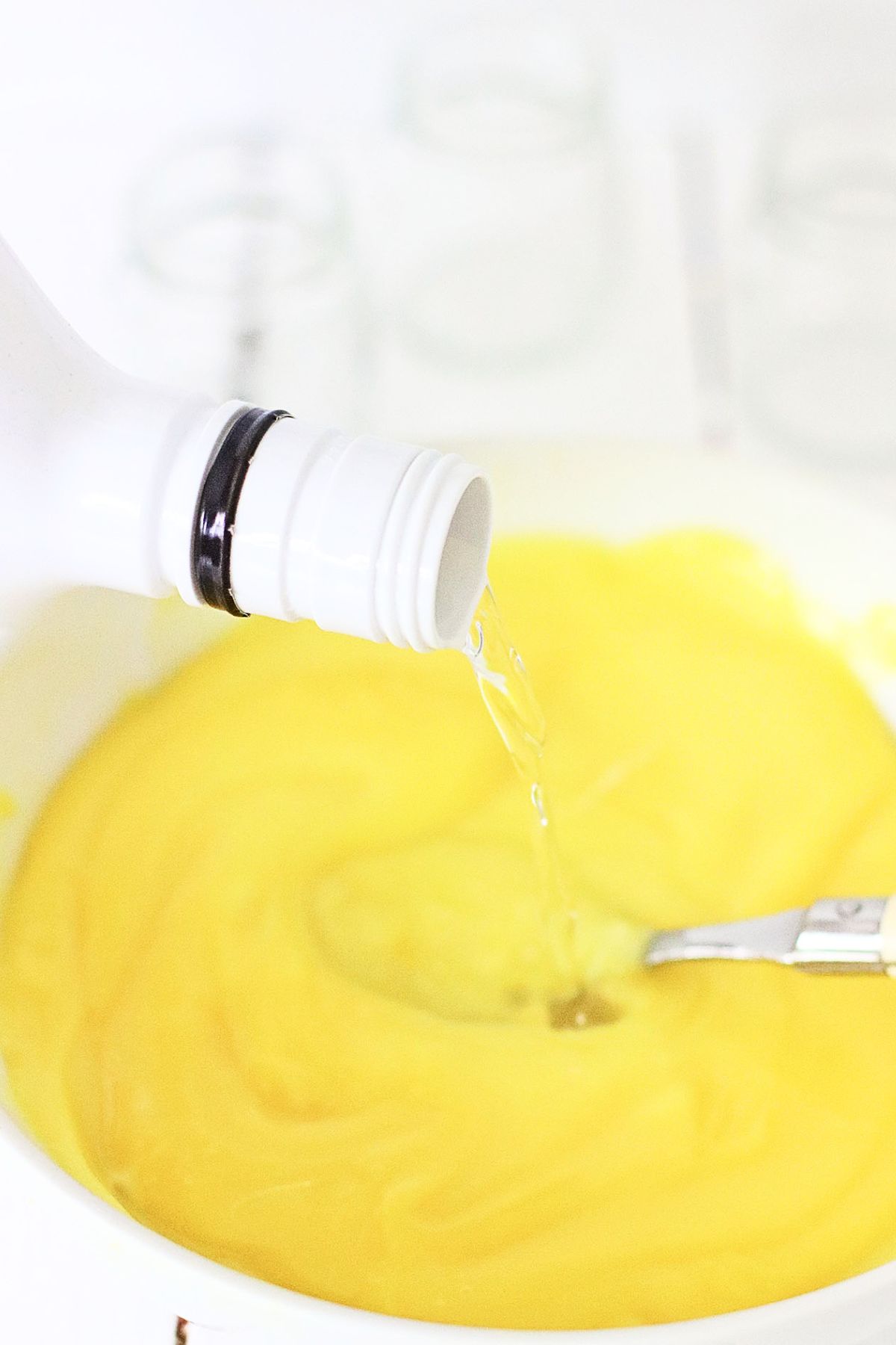 Small white bowl with banana pudding and rum being mixed together with a spoon. 