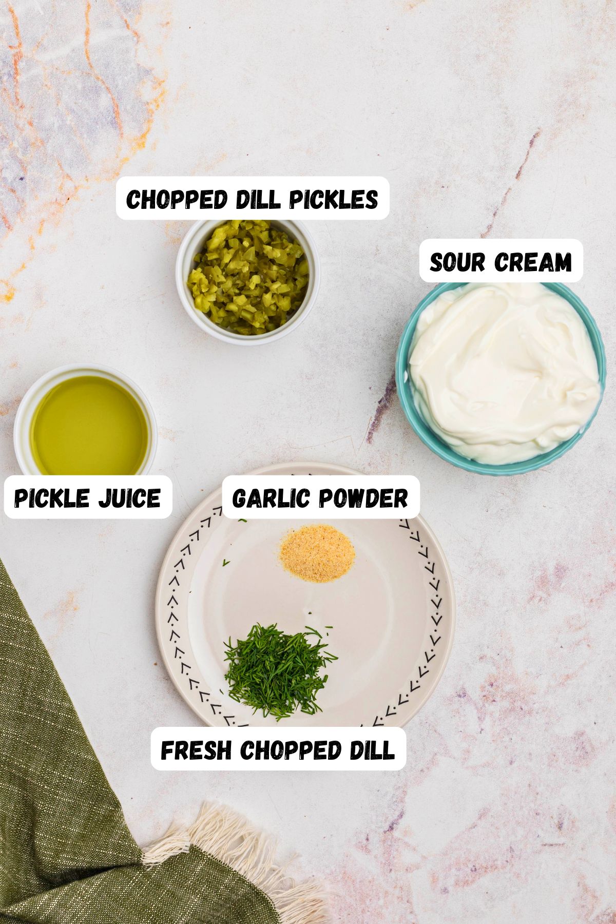 Chopped pickles, sour cream, pickle juice, and seasonings, measured out and labeled, on a marble table. 