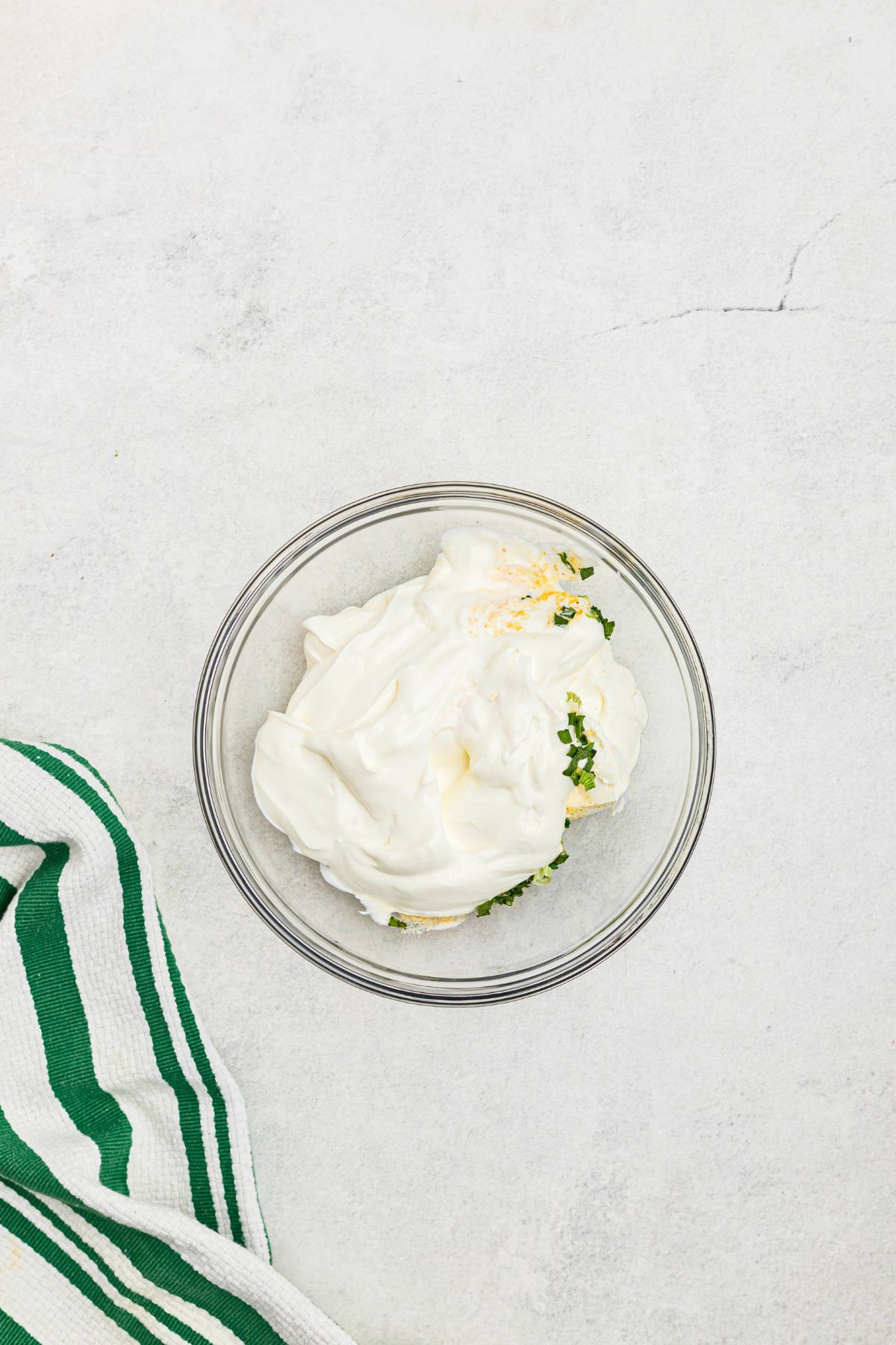 Small glass bowl with sour cream and seasonings, before being mixed into dip. 