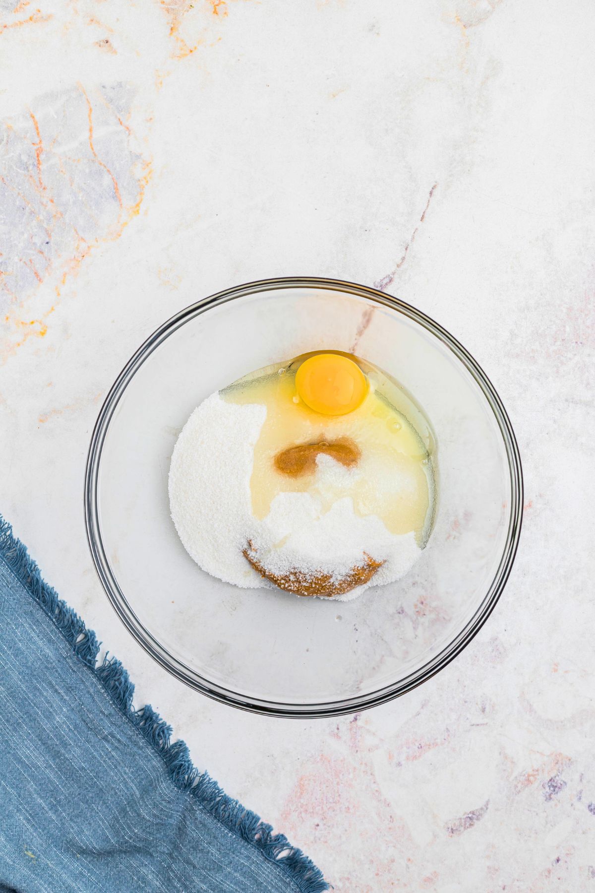 Sugar, egg, and peanut butter in a large glass bowl before being mixed together. 