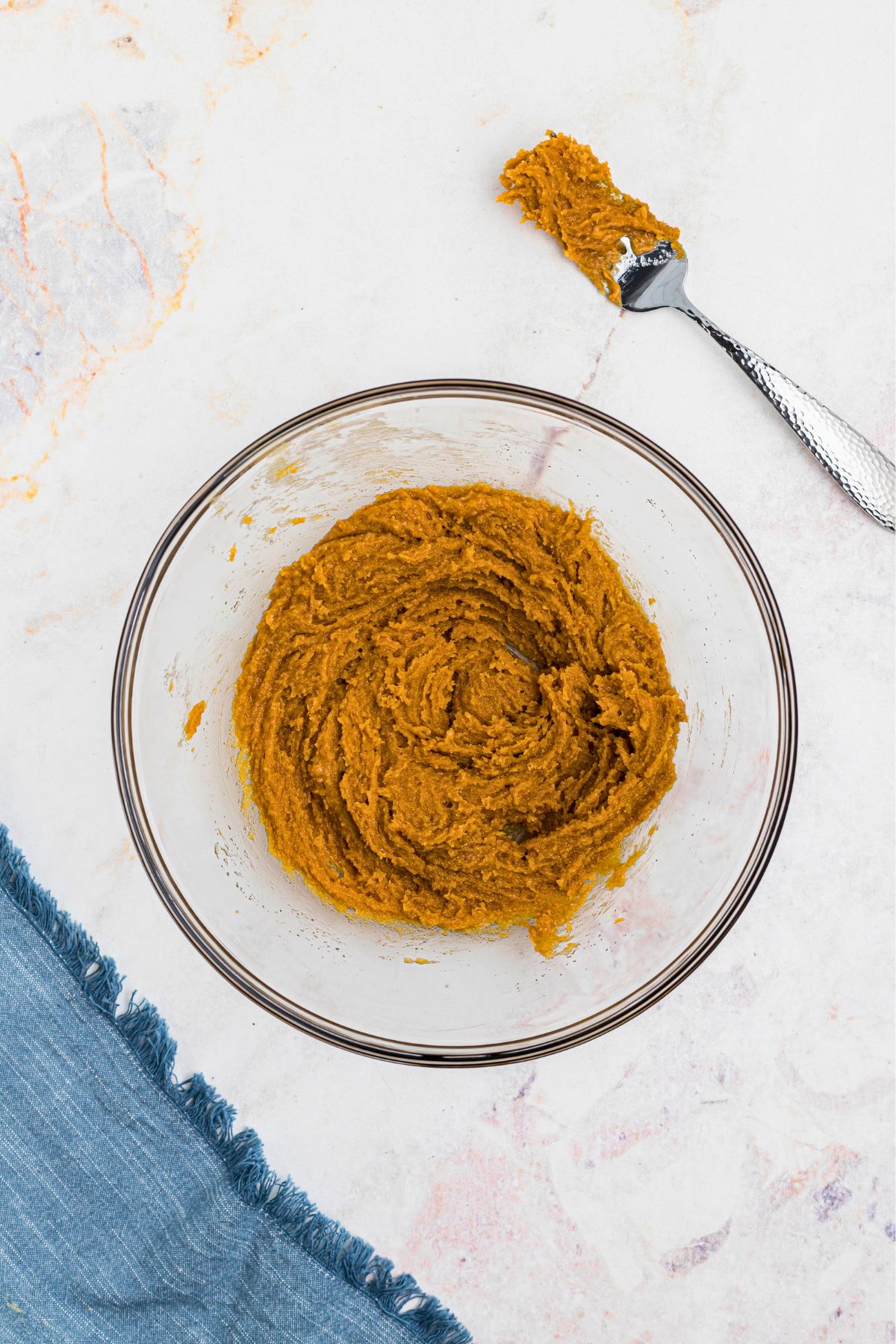 Large mixing bowl with creamy peanut butter cookie dough, on a marble table. 
