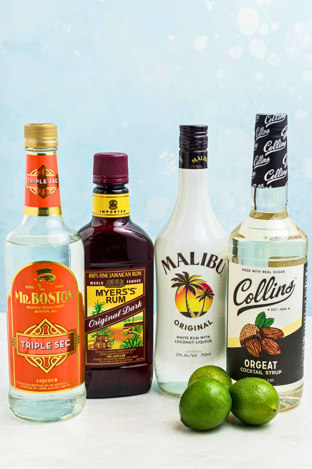 Light rum, dark rum, Orgeat and Triple sec in bottles, with a few limes on the table. 