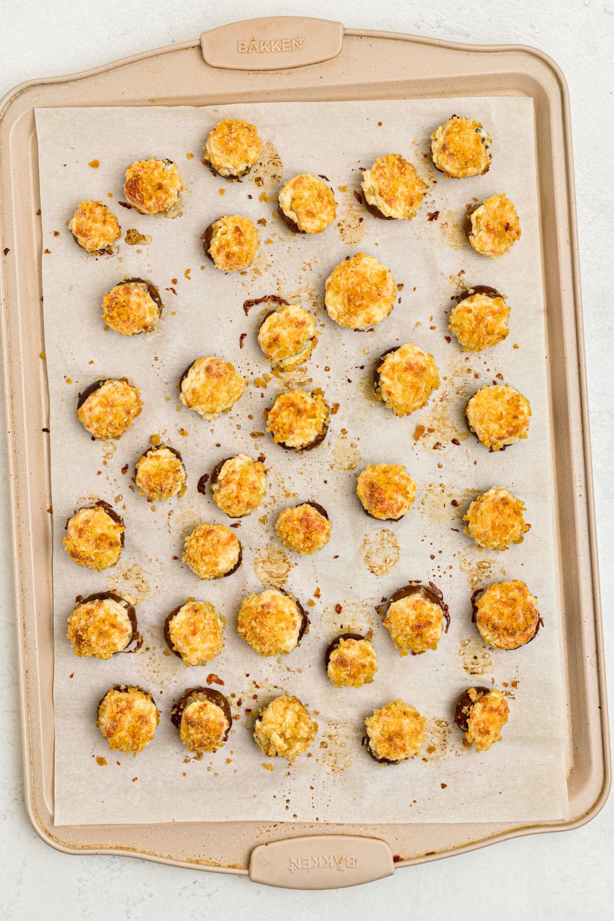 Stuffed mushrooms on a baking sheet, lined with parchment paper, after baking. 