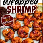 Crispy bacon wrapped around shrimp, coated with BBQ sauce mixture, on a light green plate with lemon slices and serving tongs on the table.