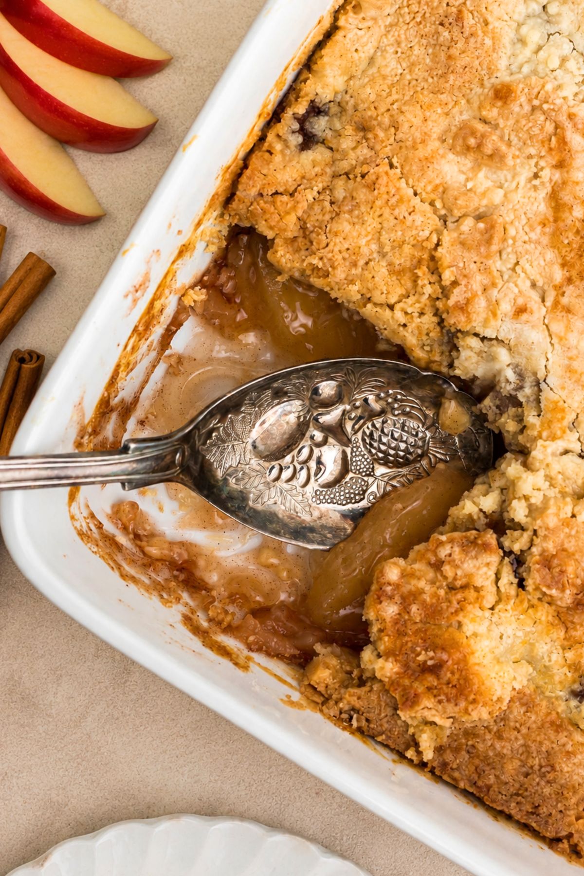 Golden brown crusted apple dump cake in a white baking dish on a marble table.