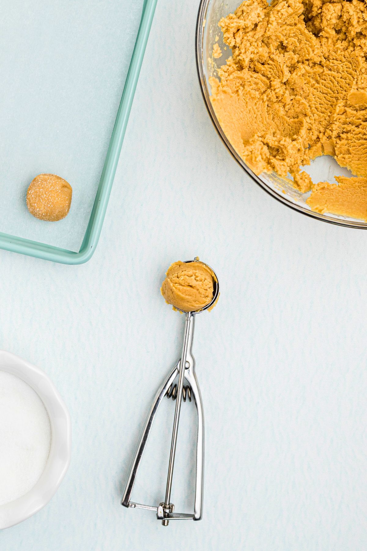 Peanut butter cookie dough being scooped into 1 inch dough balls before being rolled into sugar. 