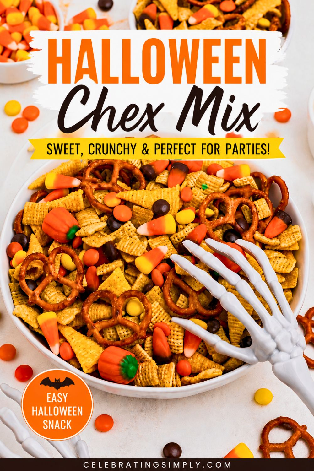Large white bowl filled with Chex mix, pretzels, candy corn, and candies, with some scattered around the table and a scooper skeleton hand on top of the bowl.