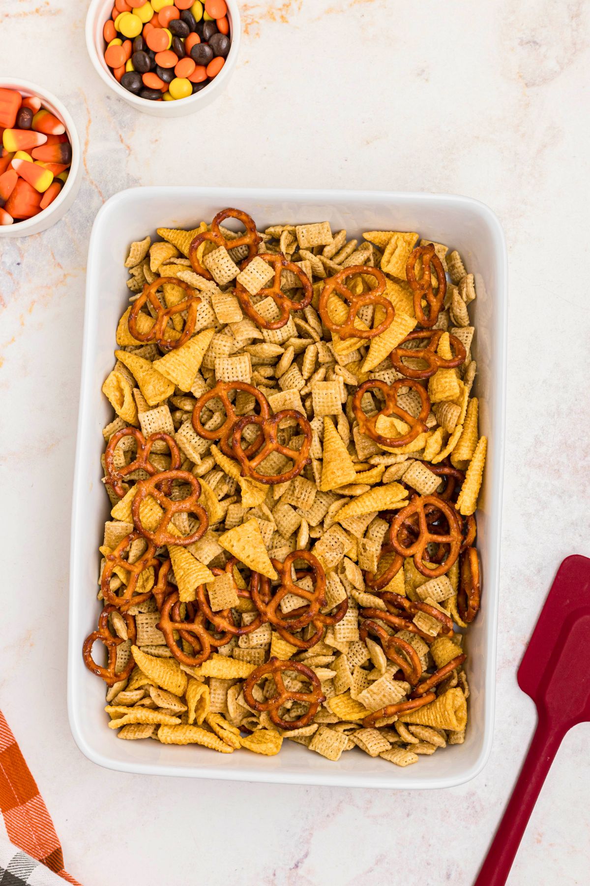 Chex mix ingredients mixed together in a 9x11 baking dish before being baked together. 