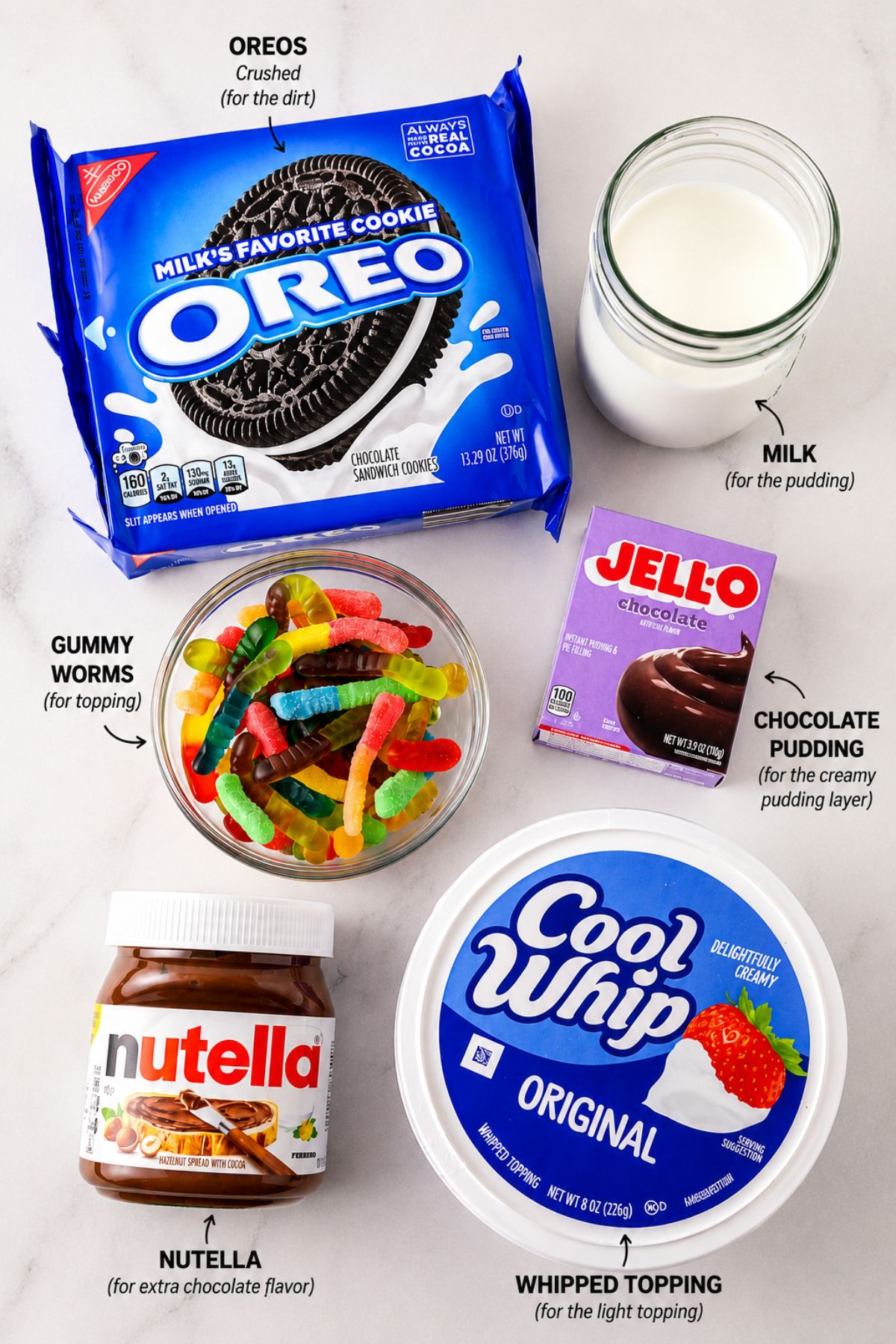 Oreoes, cool whip, glass of milk, bowl of gummy worms, and a tub of Nutella, on a white marble table.