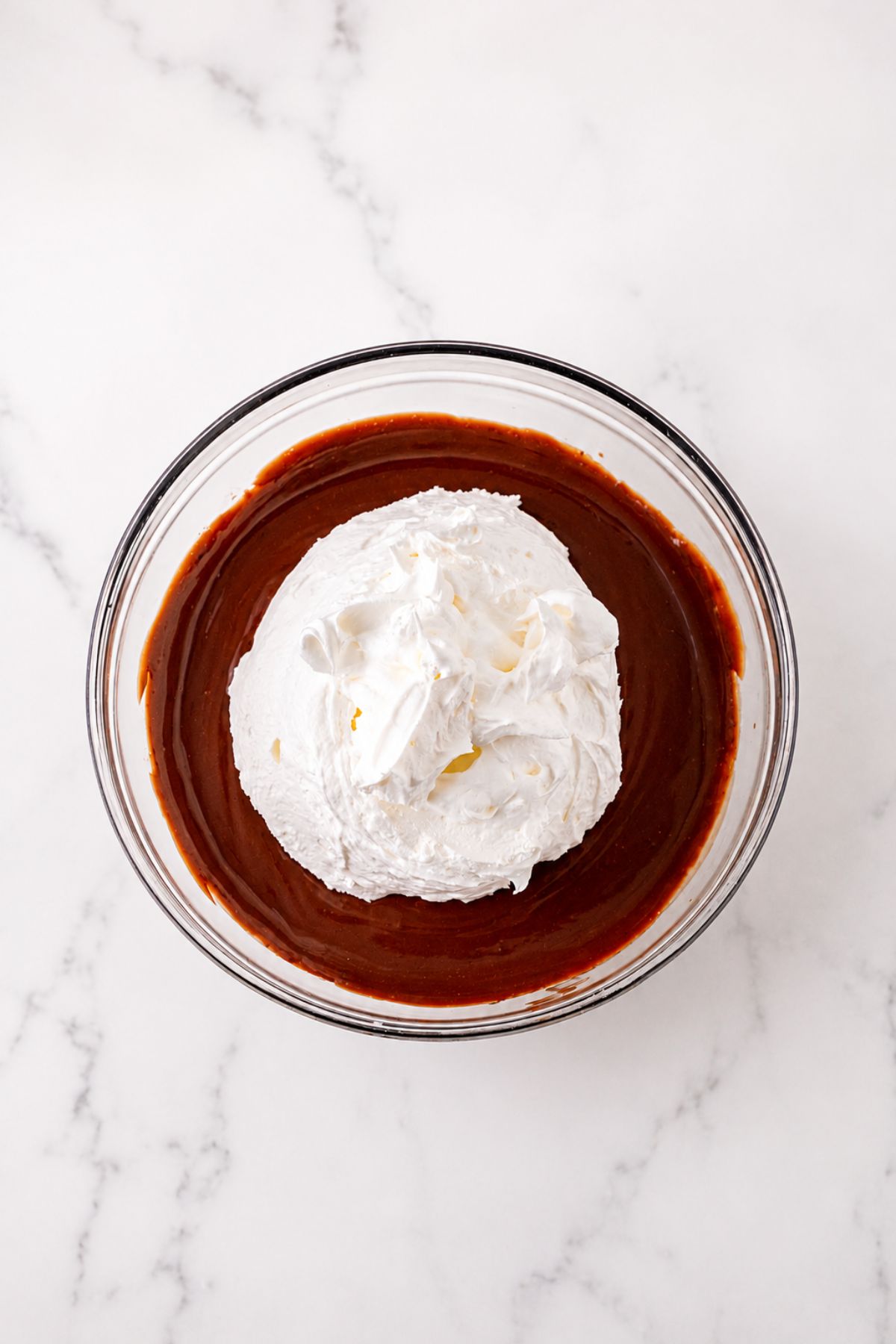 Large clear mixing bowl, filled with pudding, then topped with whipped cream, before mixing together.