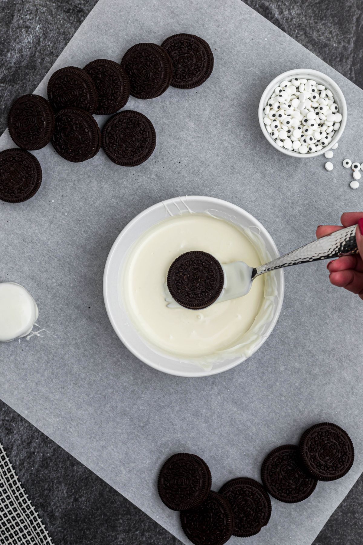 White chocolate melted in a dish, with Oreo cookie dipped in the center, on parchment paper.