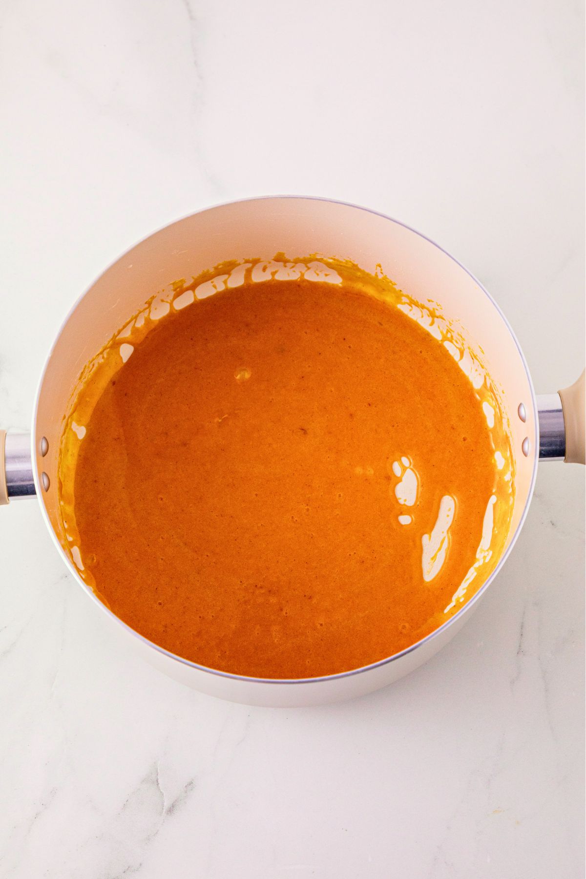 Marshmallows, butter, and pumpkin puree, mixed with orange food gel, in a large bowl. 