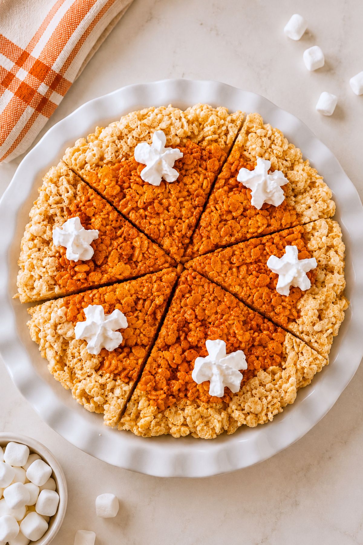Whole pie of krispie treats in a pie plate, after cutting, on a marble table.
