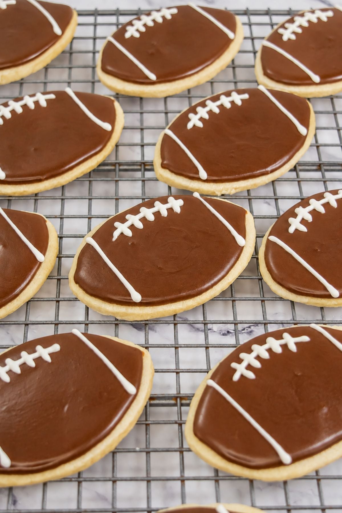 Football shaped sugar cookies, on a cooling rack.