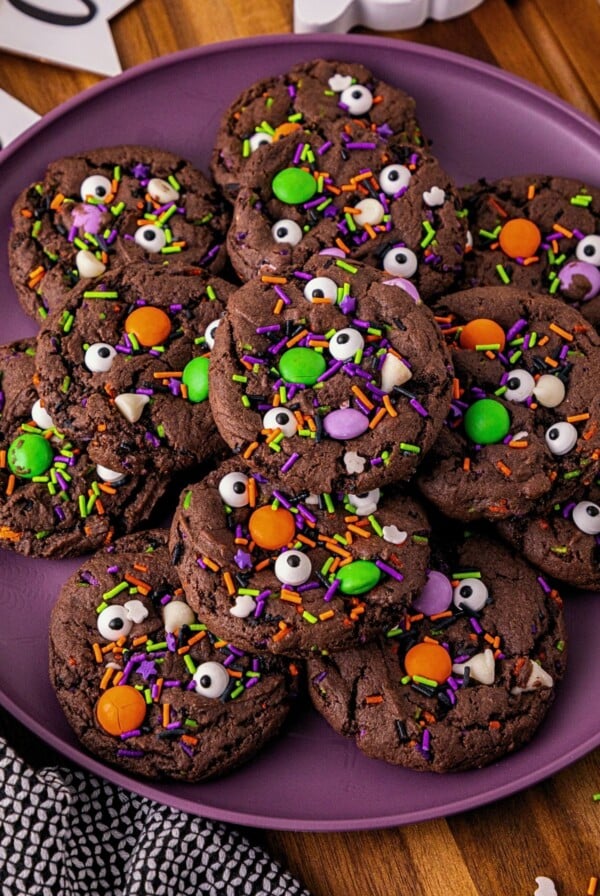 Chocolate cake mix cookies with sprinkles and candies mixed in, on a purple plate.