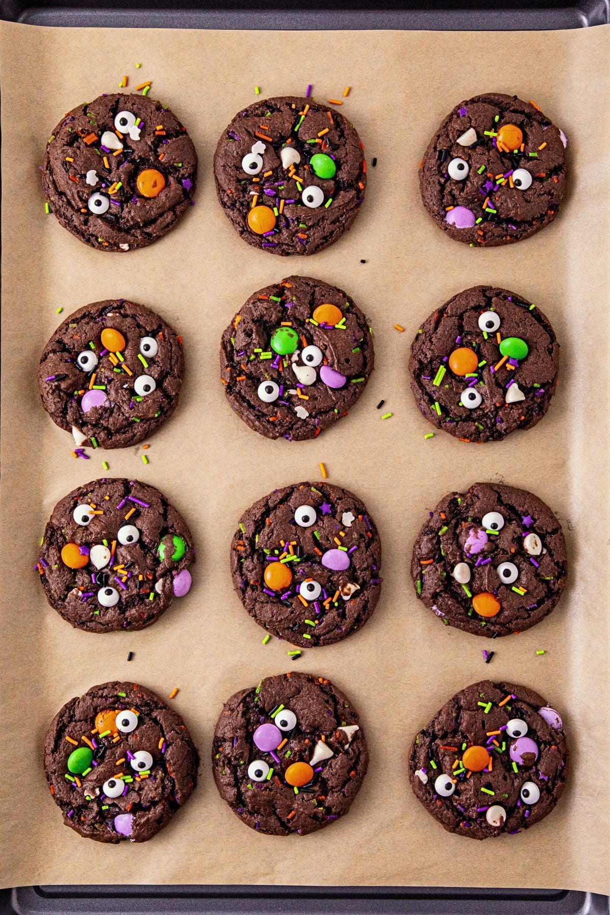 Chocolate cake mix cookies on a baking sheet lined with parchment paper, after being baked.