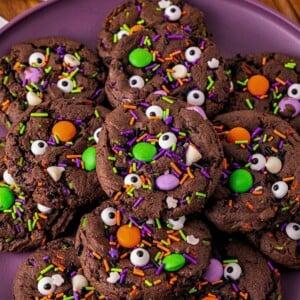 Chocolate cake mix cookies with sprinkles and candies mixed in, on a purple plate.