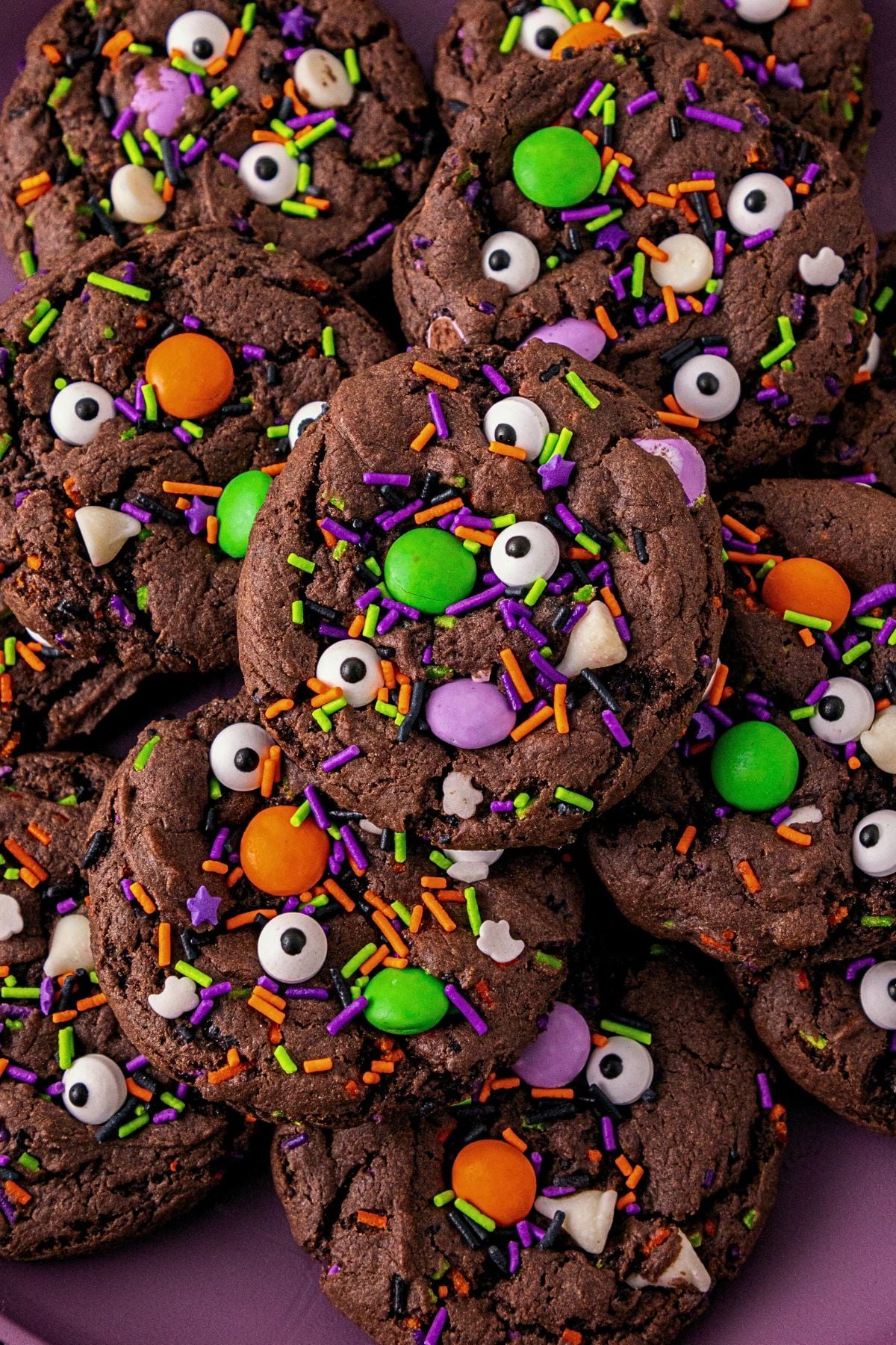 Chocolate cake mix cookies with sprinkles and candies mixed in, on a purple plate.