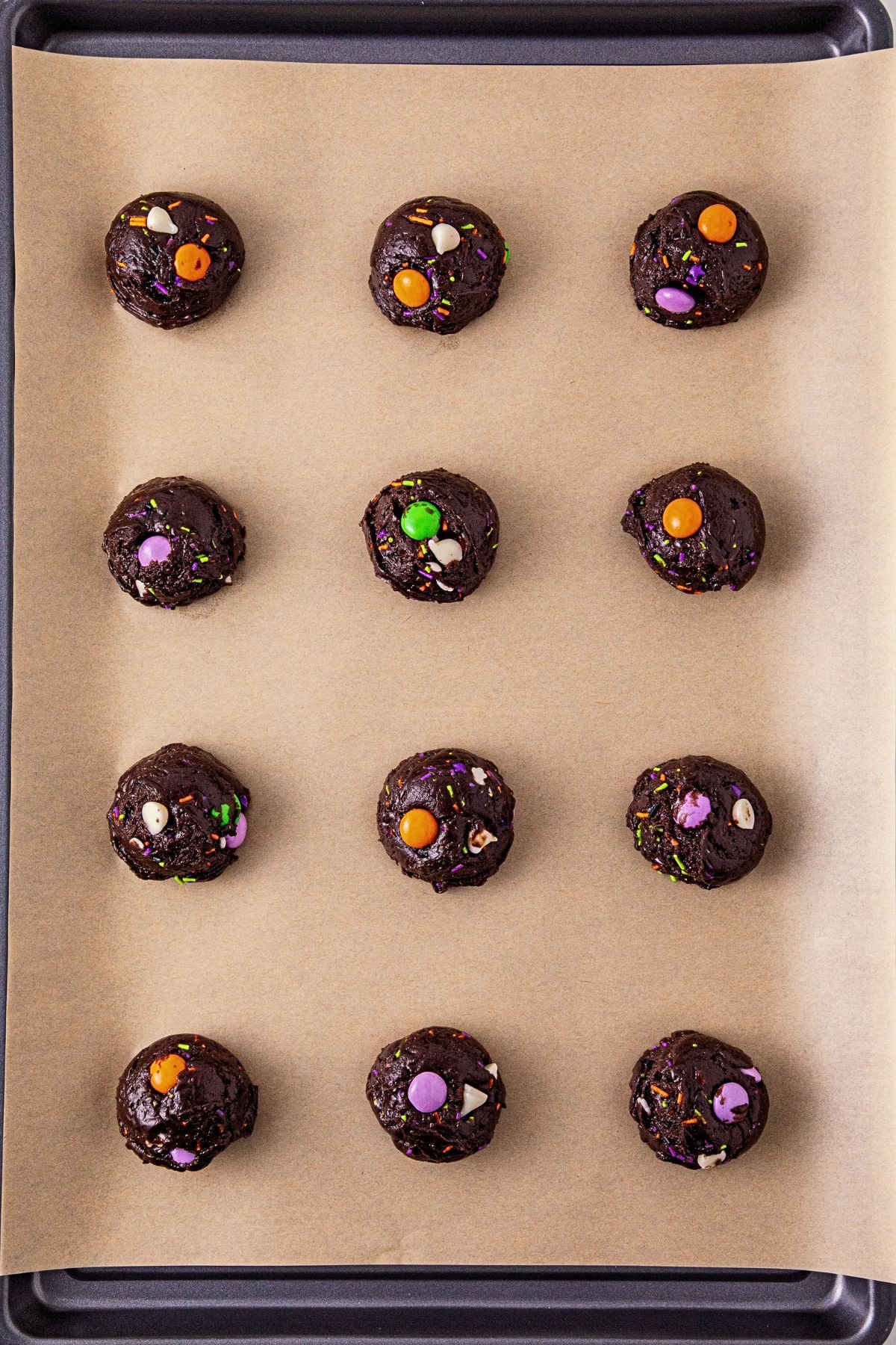 Chocolate cake mix cookie dough rolled and placed on a baking sheet lined with parchment paper.