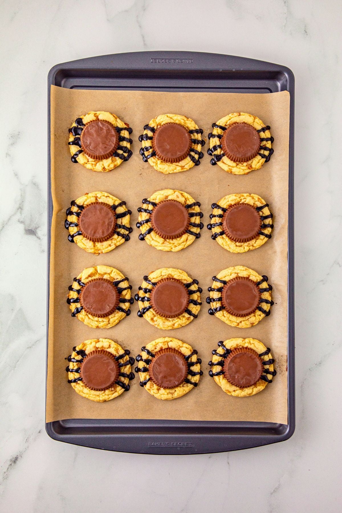 Baked cookies with a peanut butter cup placed on top of each cookie for the spider body.