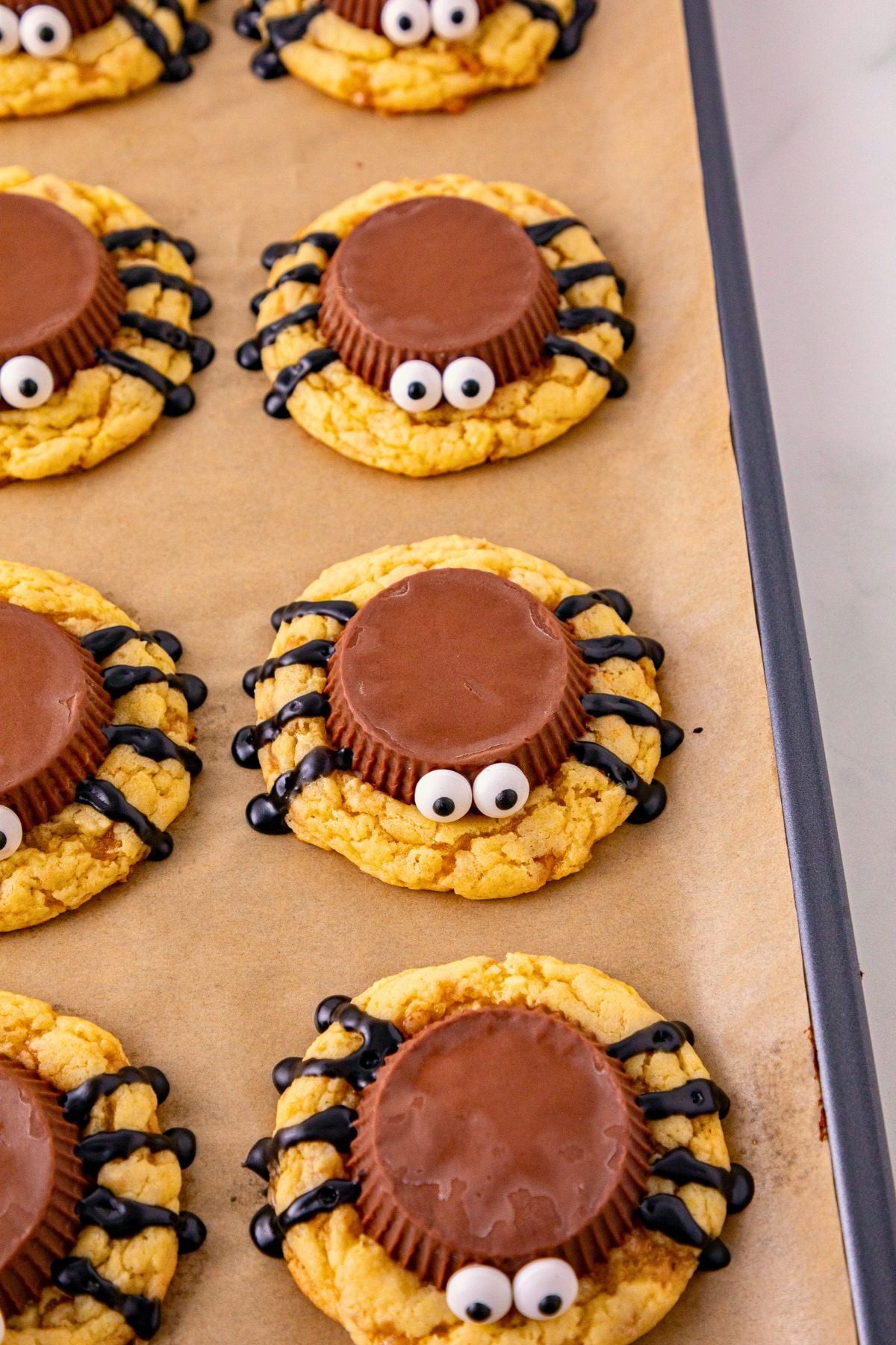 Baked cookies with a peanut butter cup placed on top of each cookie for the spider body and candy eyes. 