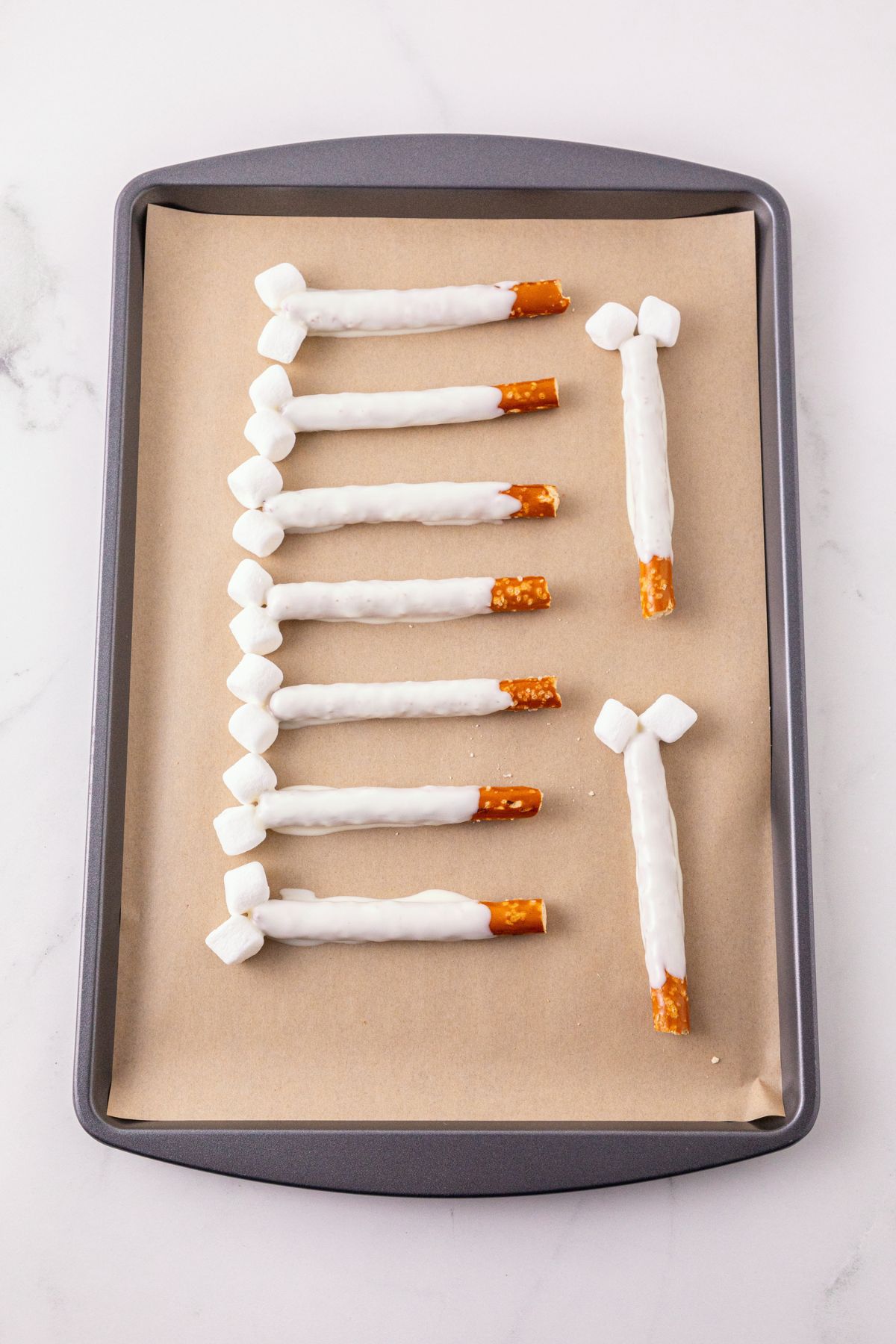 Pretzel Rods dipped in white chocolate, placed on a parchment paper lined baking sheet to harden. 