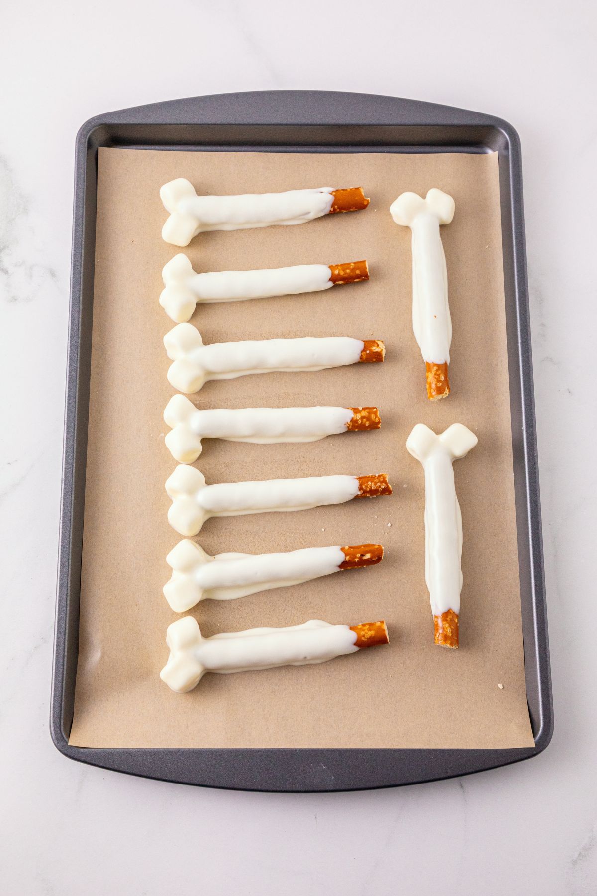 Pretzel rods and marshmallows double dipped in melting chocolate, then placed on parchment paper lined baking sheet to harden. 