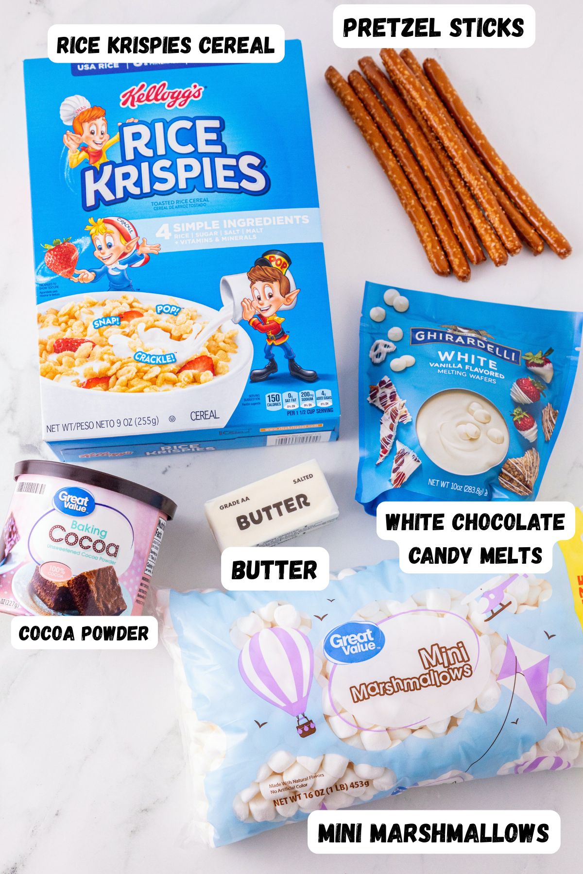 Rice Krispie cereal, cocoa powder, pretzels, marshmallows, butter, and melting chocolates, labeled on a white marble table. 