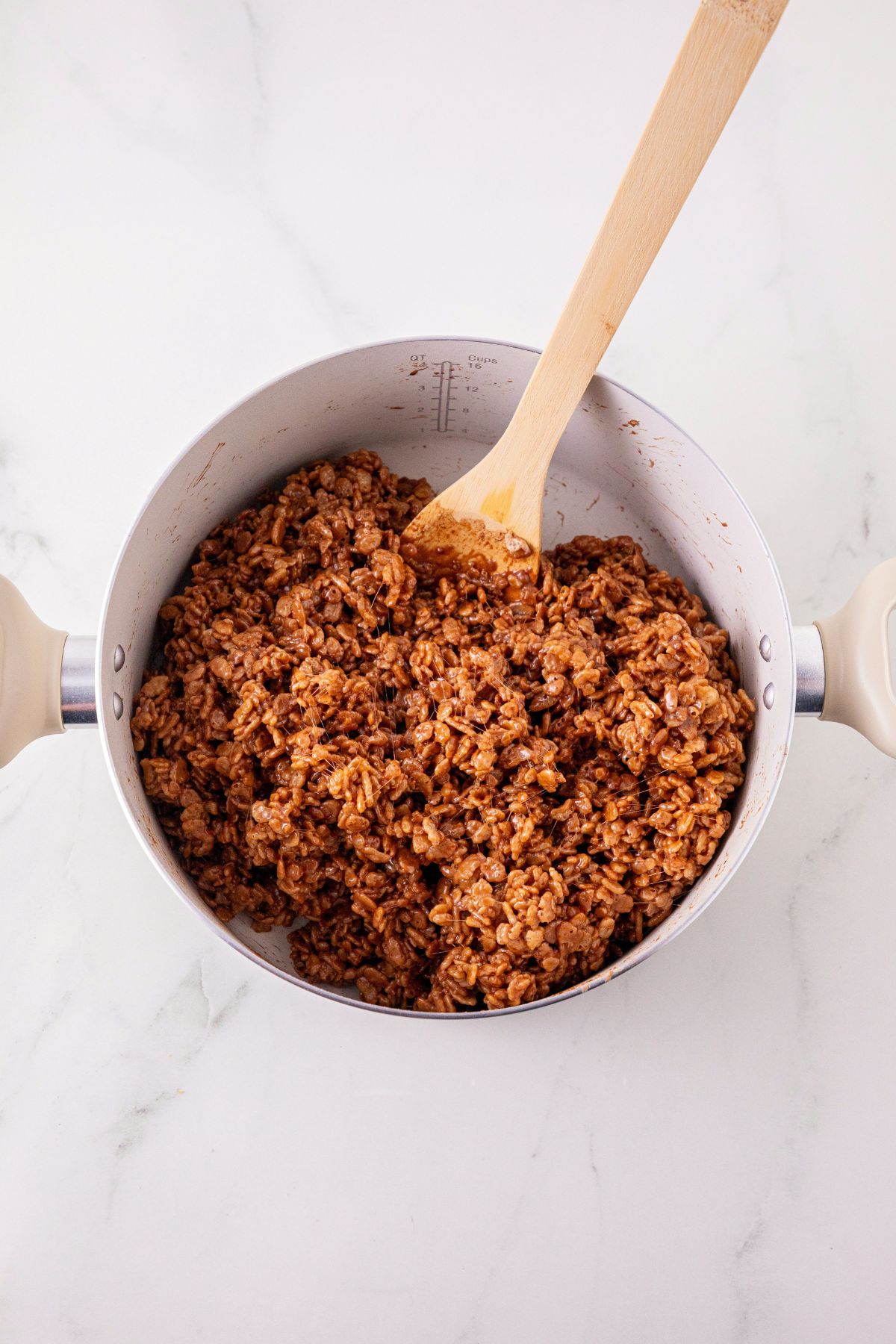 Rice Krispies cereal mixed with melted butter, marshmallows, and cocoa powder, in a large saucepan. 