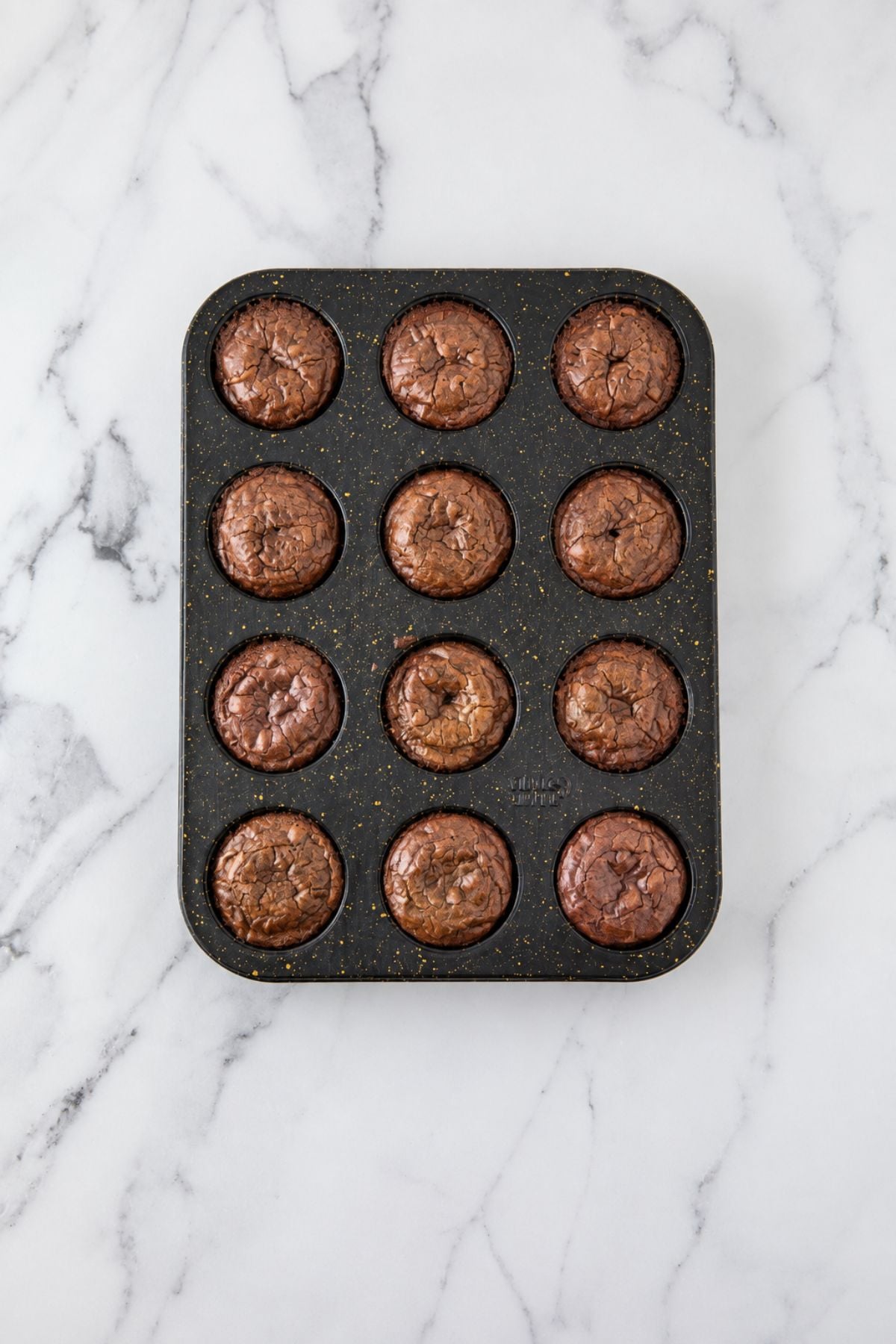 Baked brownies in a muffin pan after baking.