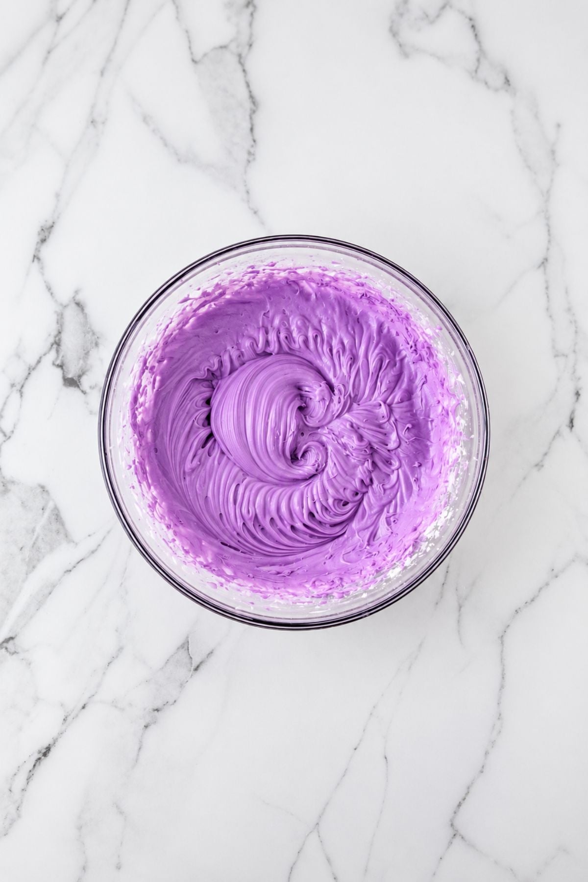 Purple Frosting in a clear glass mixing bowl.