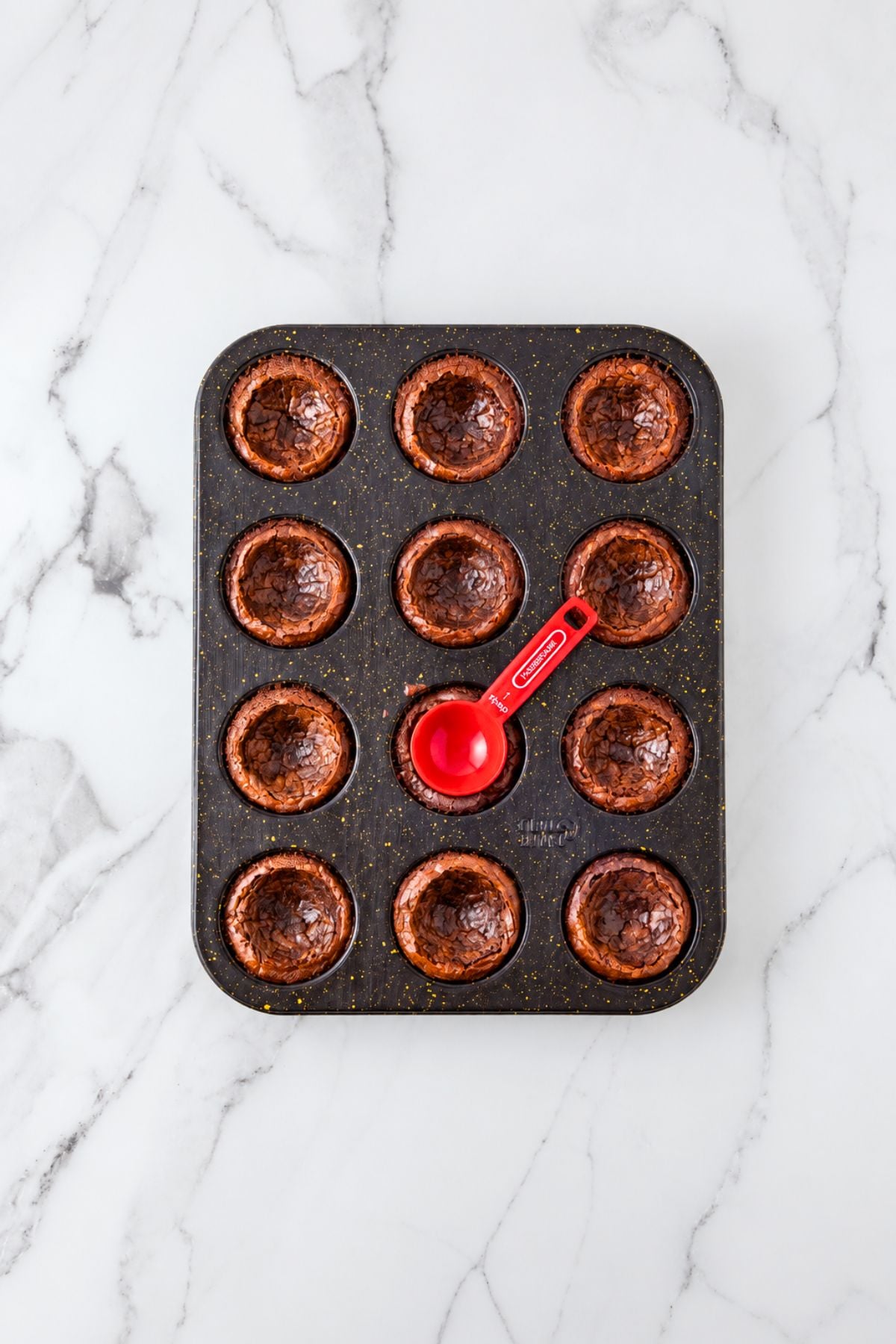 Baked brownie bites with the center pressed in with a spoon.