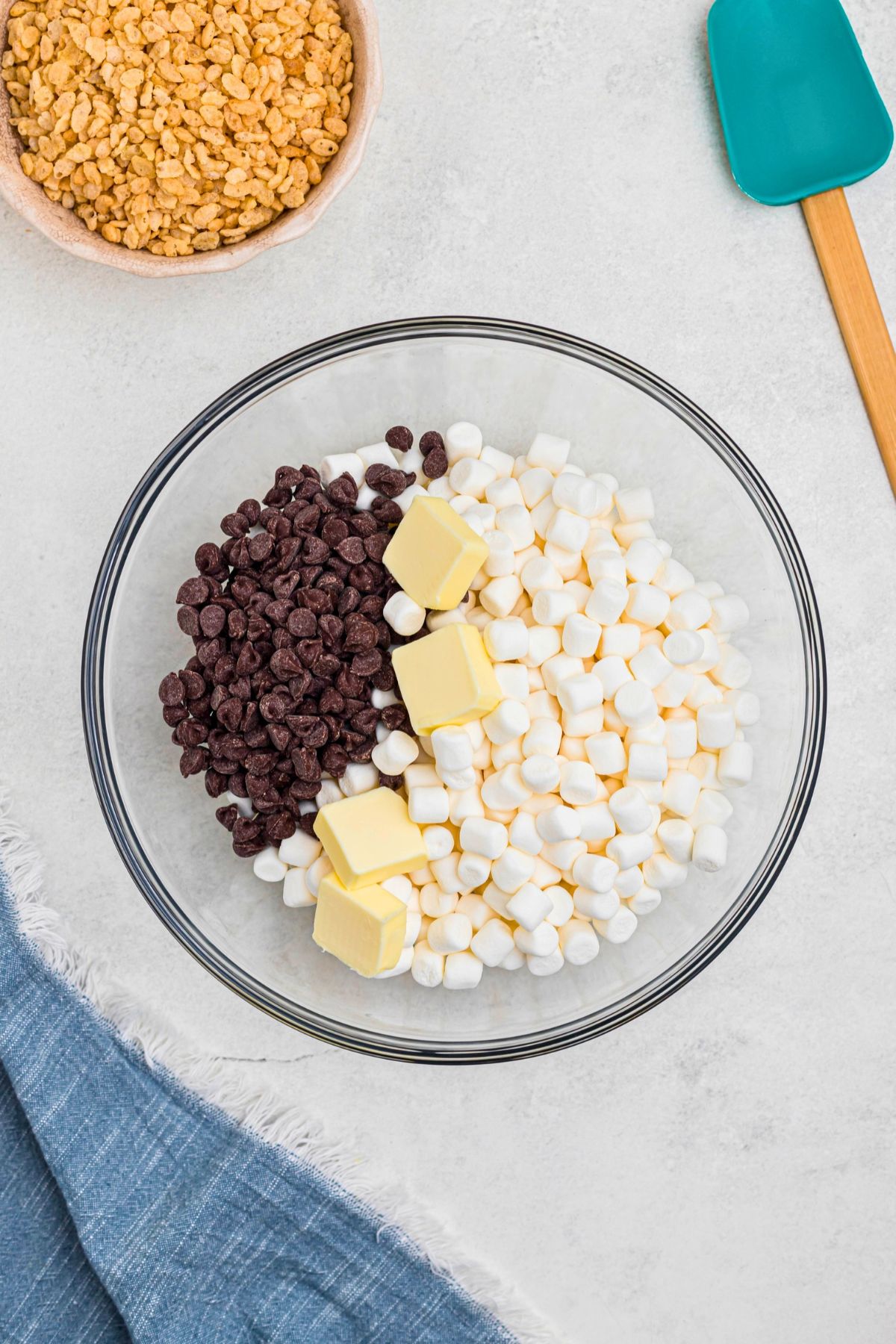 Marshmallows, chips, and butter, in a large glass bowl on a marble table. 