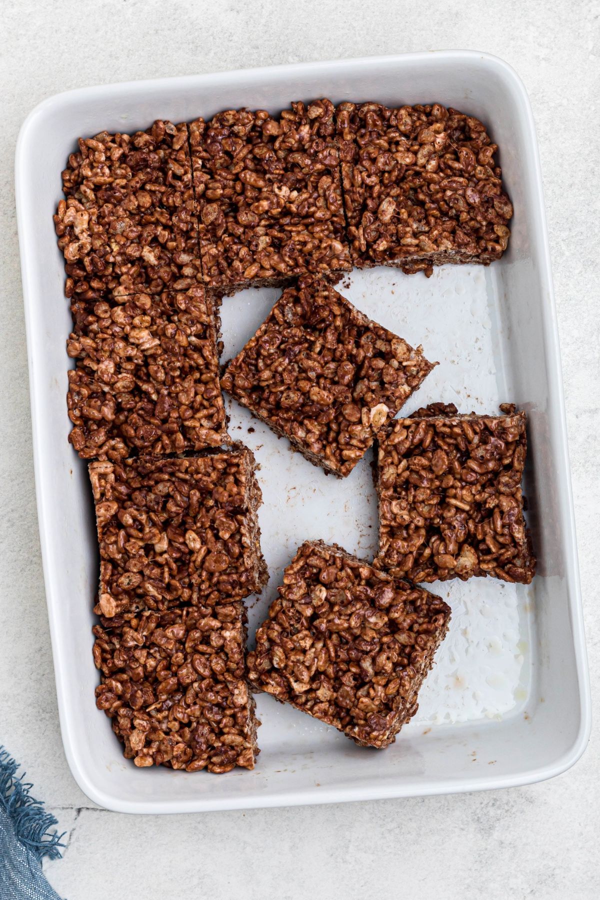 White pan filled with cut squares of chocolate krispie treats.