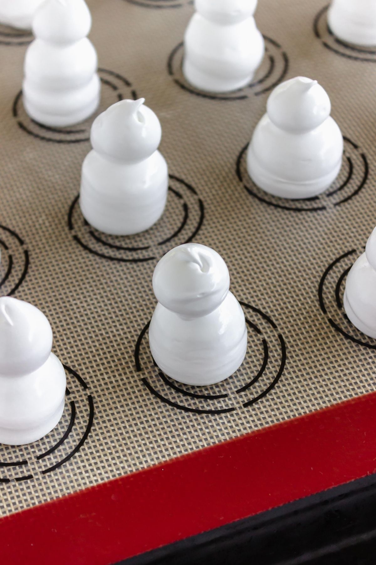 Meringues piped onto baking sheet lined with silicone baking sheet liner.