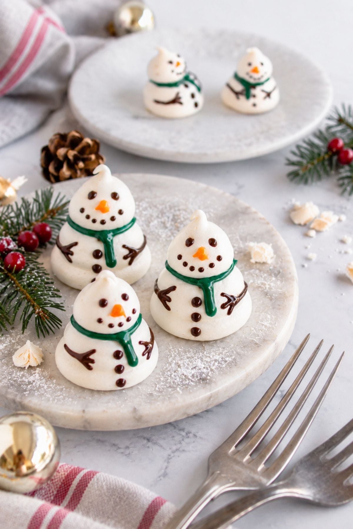 Baked snowmen on a white plate with holiday decorations around the table.