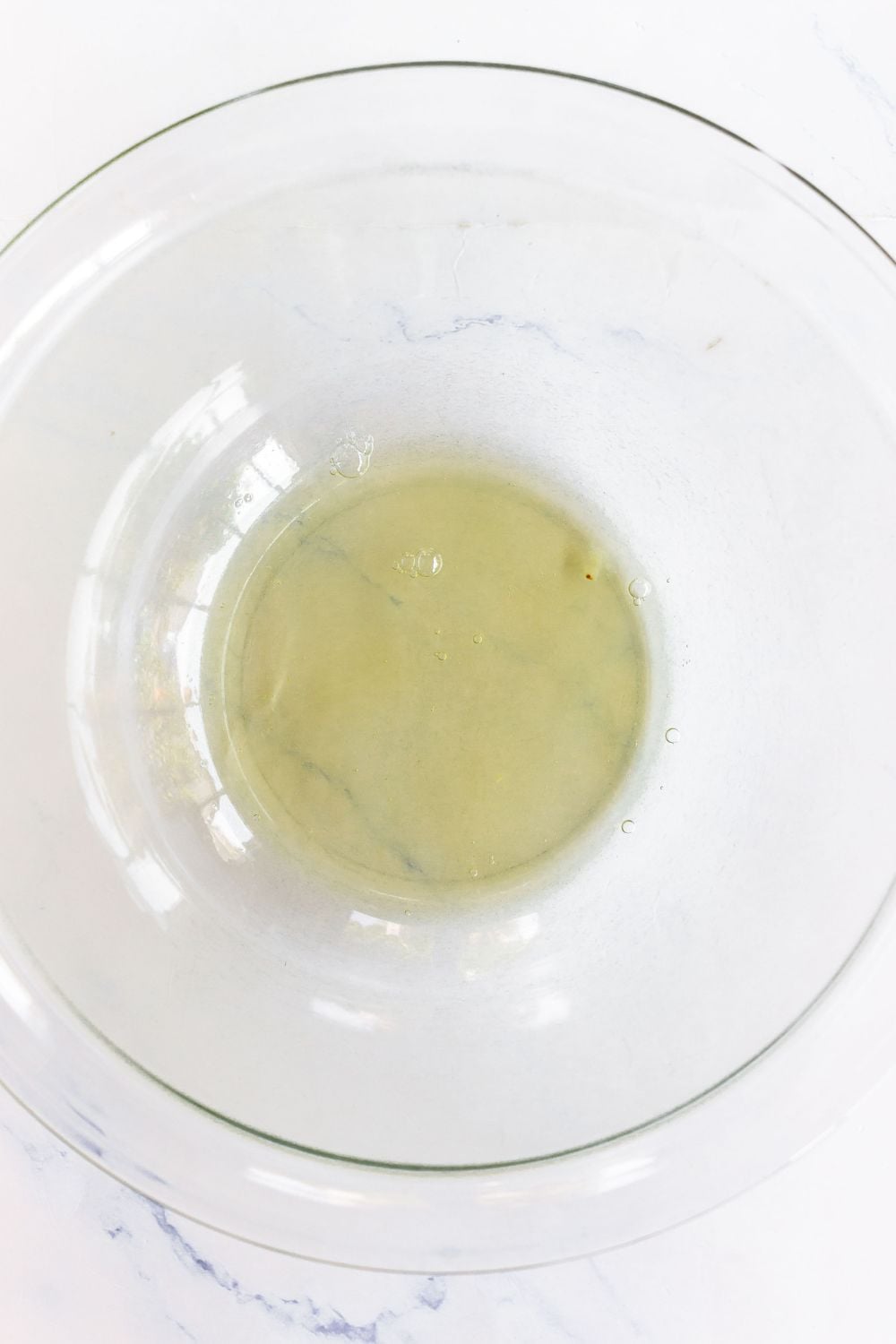 Egg whites in a clear large glass bowl before being mixed.